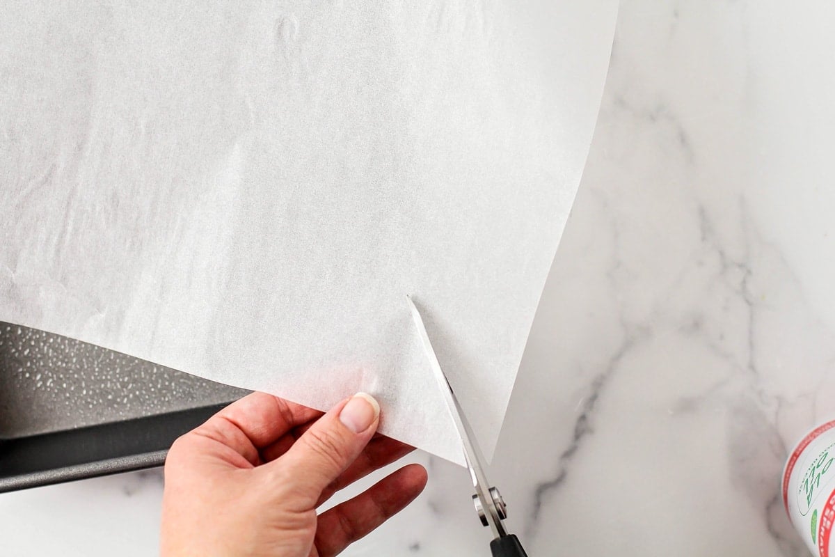Cutting the edges of a sheet of parchment paper.