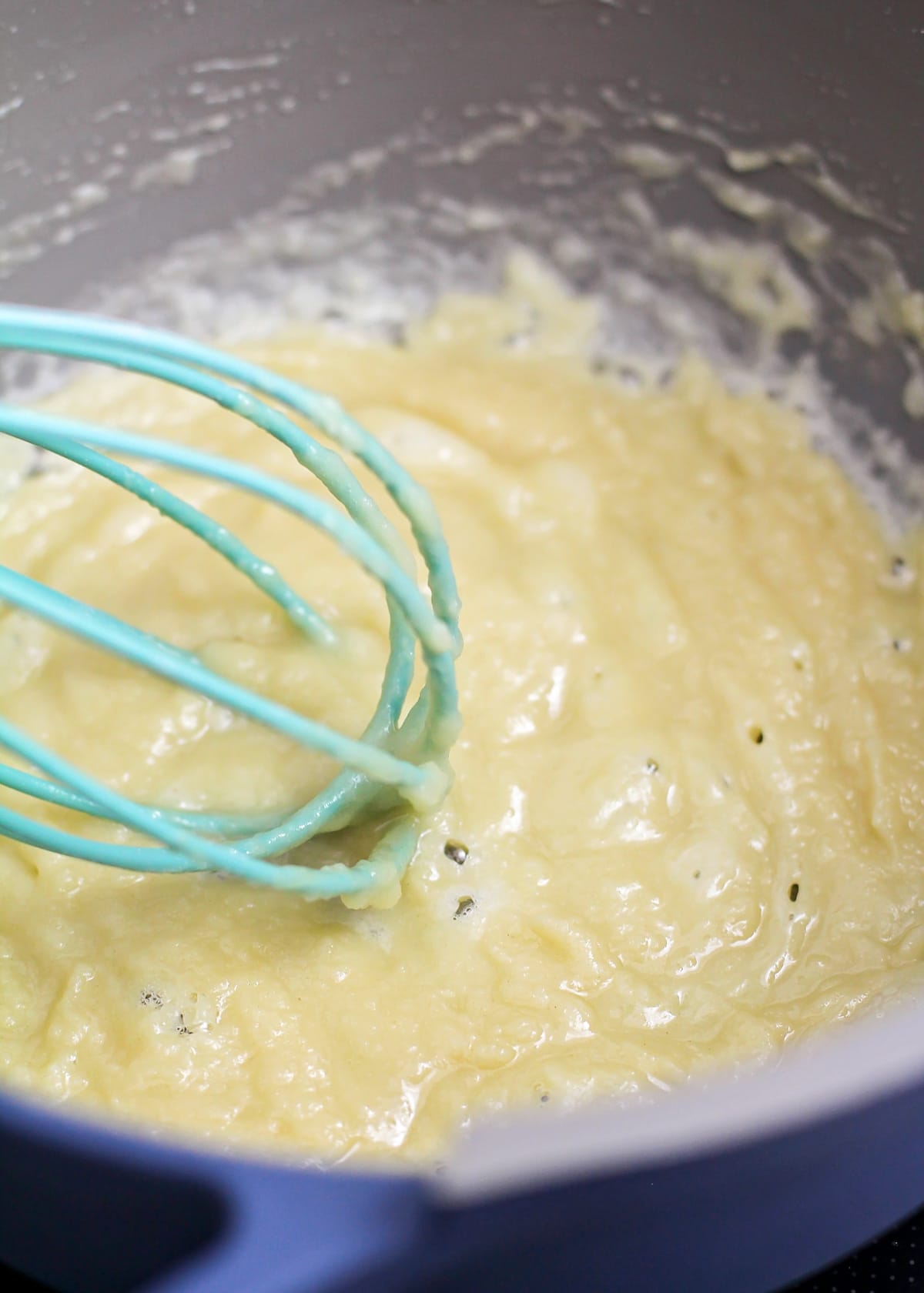 Close up of a bubbling mixture of butter and flour in a pot on the stove.