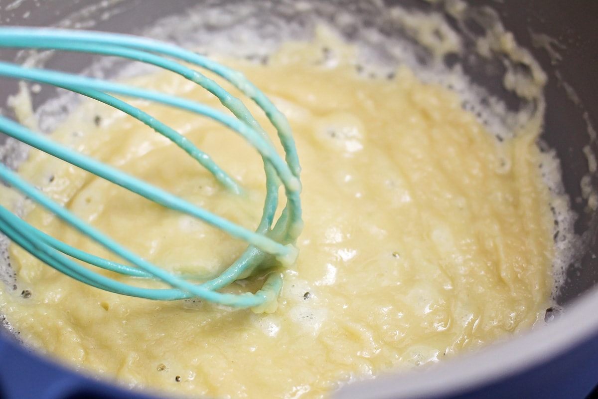 Whisking butter and flour in a pot on the stove.