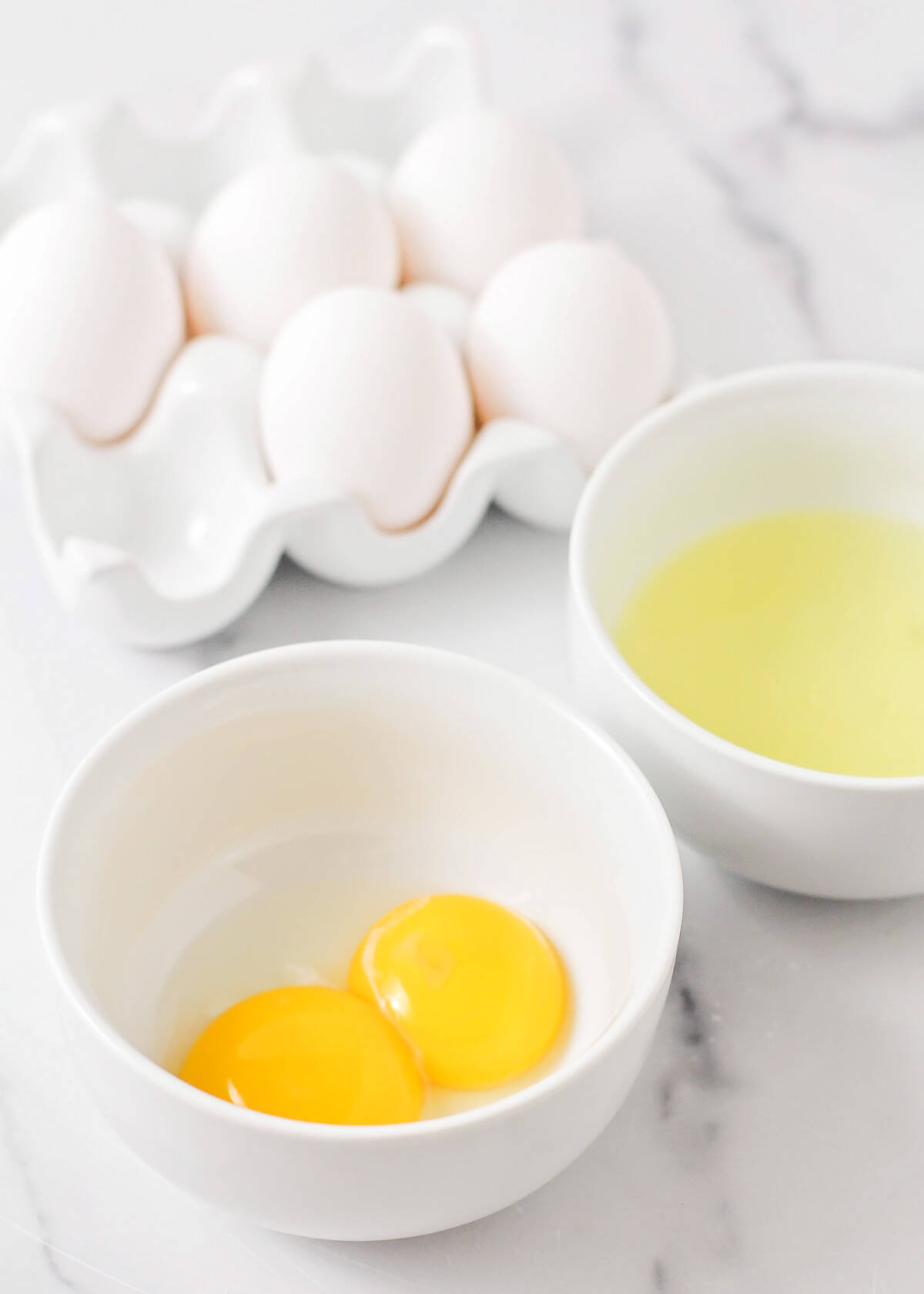 Close up of egg yolks in one bowl and whites in another for how to separate egg whites.