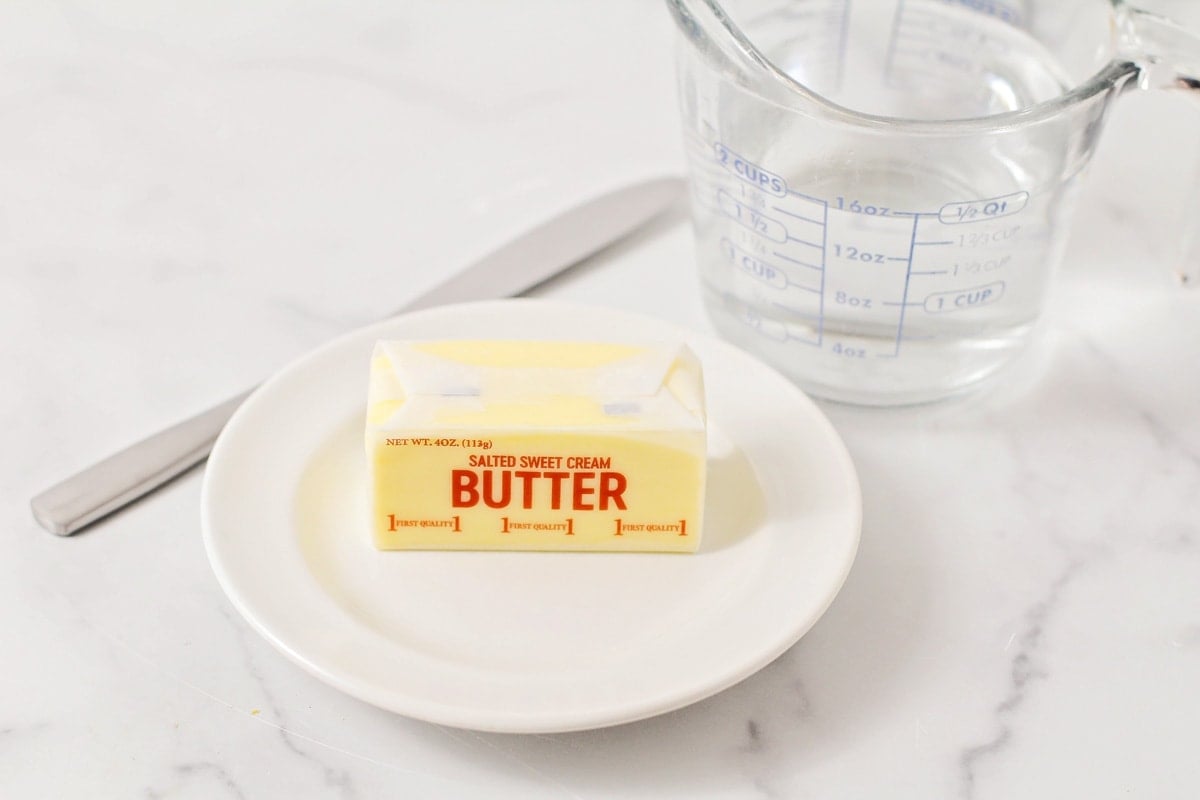 A wrapped stick of butter on a white plate.