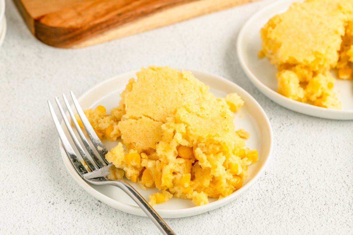 A white plate piled high with jiffy corn pudding with a fork.