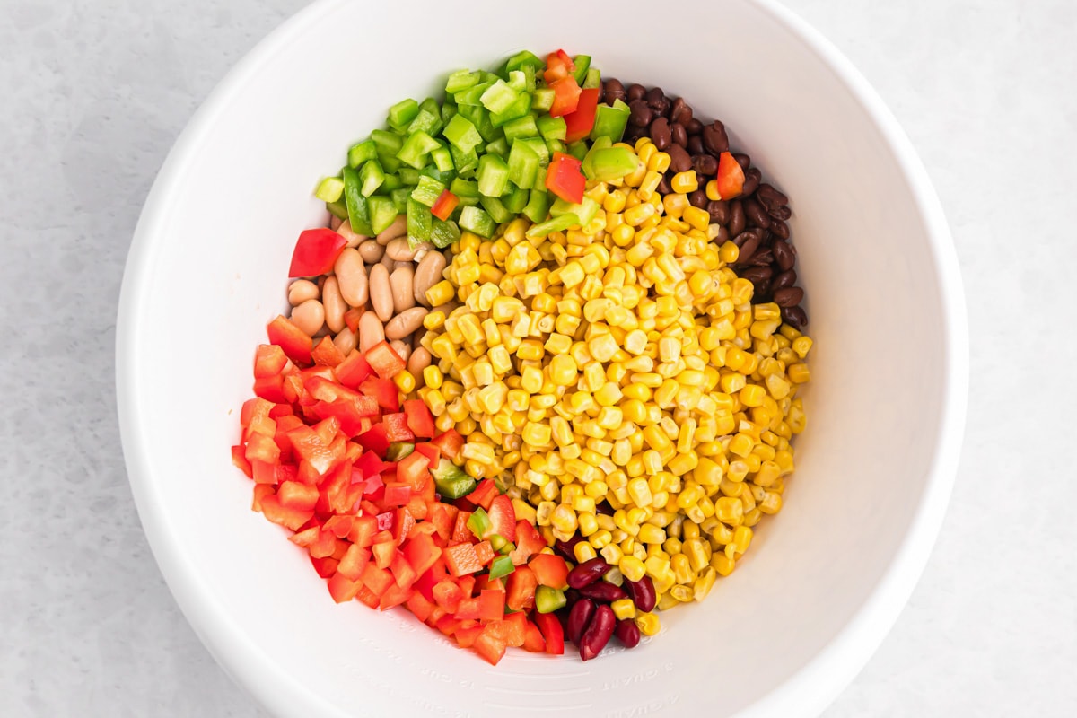 Chopped peppers, corn, and beans in a white bowl ready to be mixed.