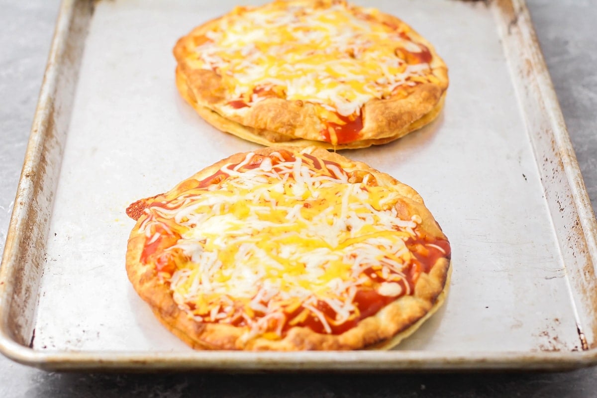 Two backed tortillas pizzas topped with melted cheese.