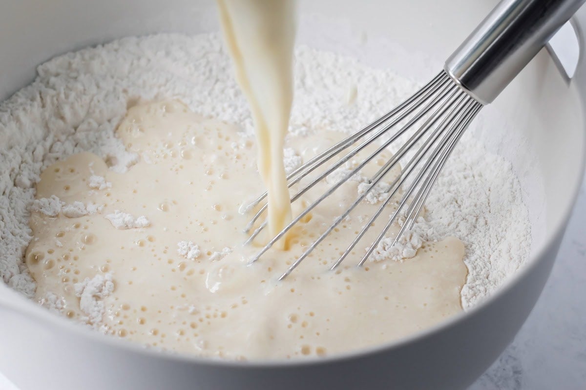 Adding wet ingredients to dry ingredients for buttermilk pancake batter.