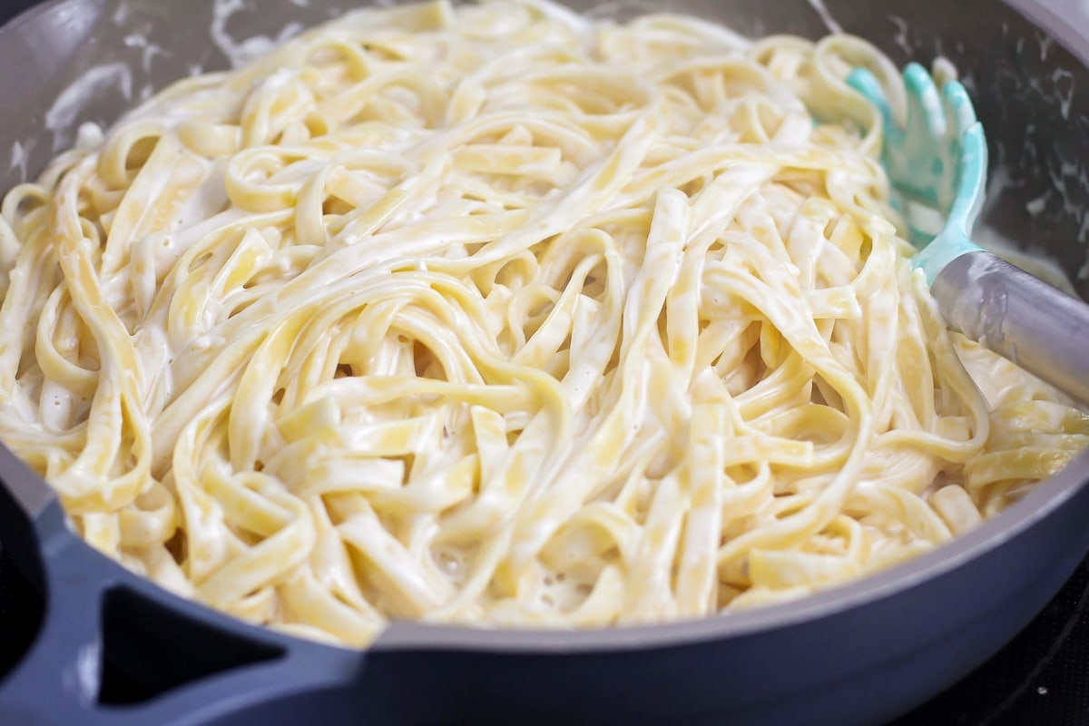Mixing pasta with creamy cheese sauce.