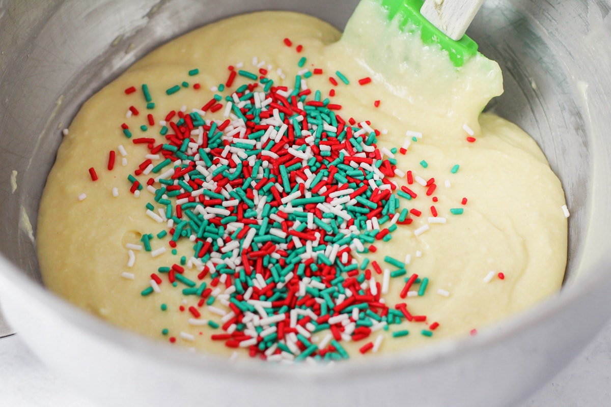 Mixing sprinkles into Christmas cupcake batter.