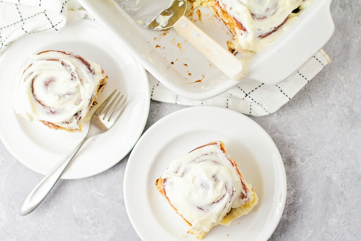 Frosted cinnamon rolls on white plates.
