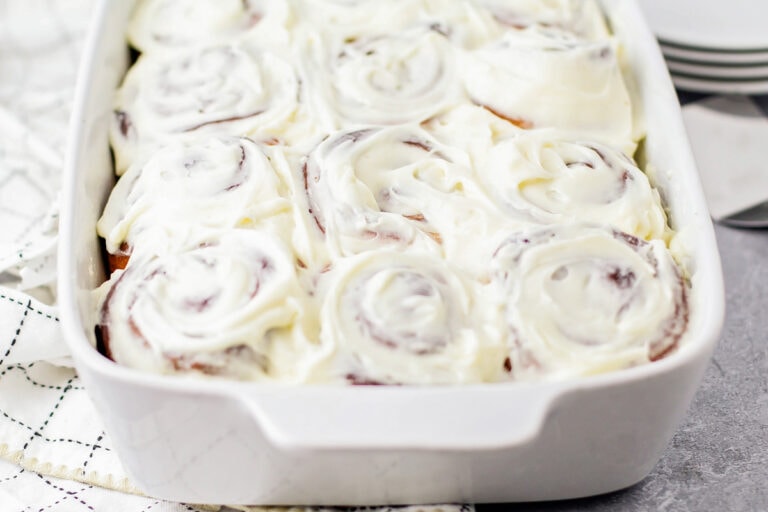Homemade cinnamon rolls with the best cinnamon roll icing recipe spread on top.