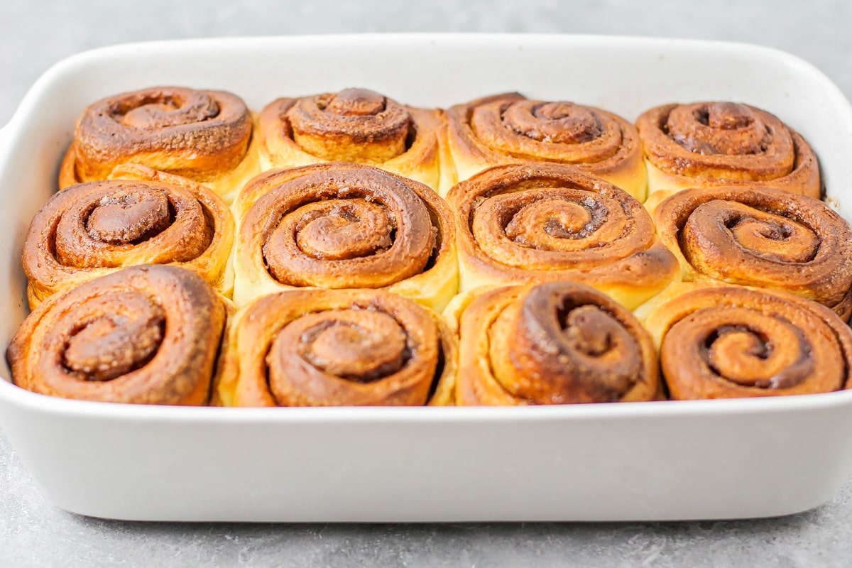 Baked, unfrosted cinnamon rolls in baking dish.
