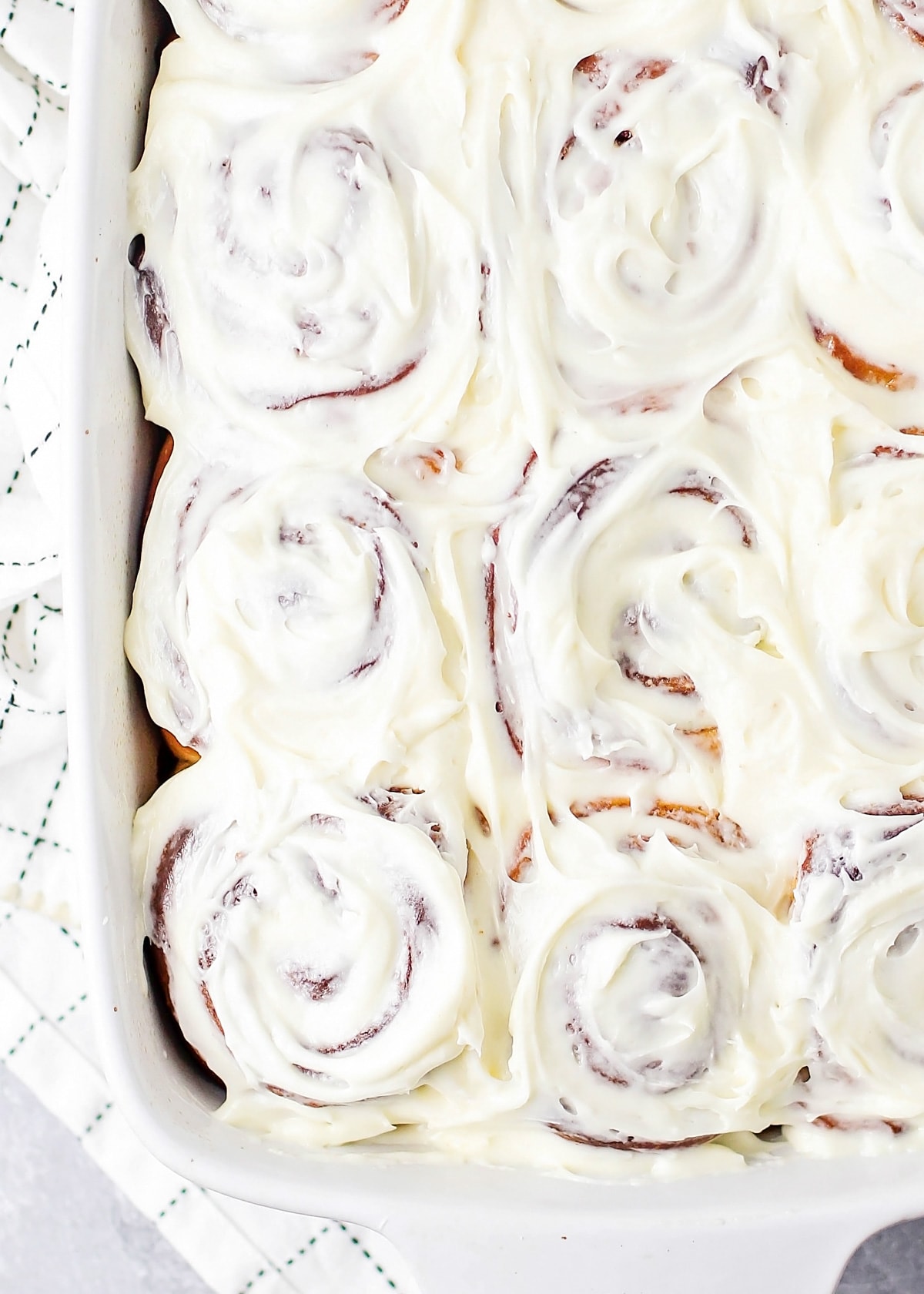 Homemade cinnamon rolls frosted and in baking dish.