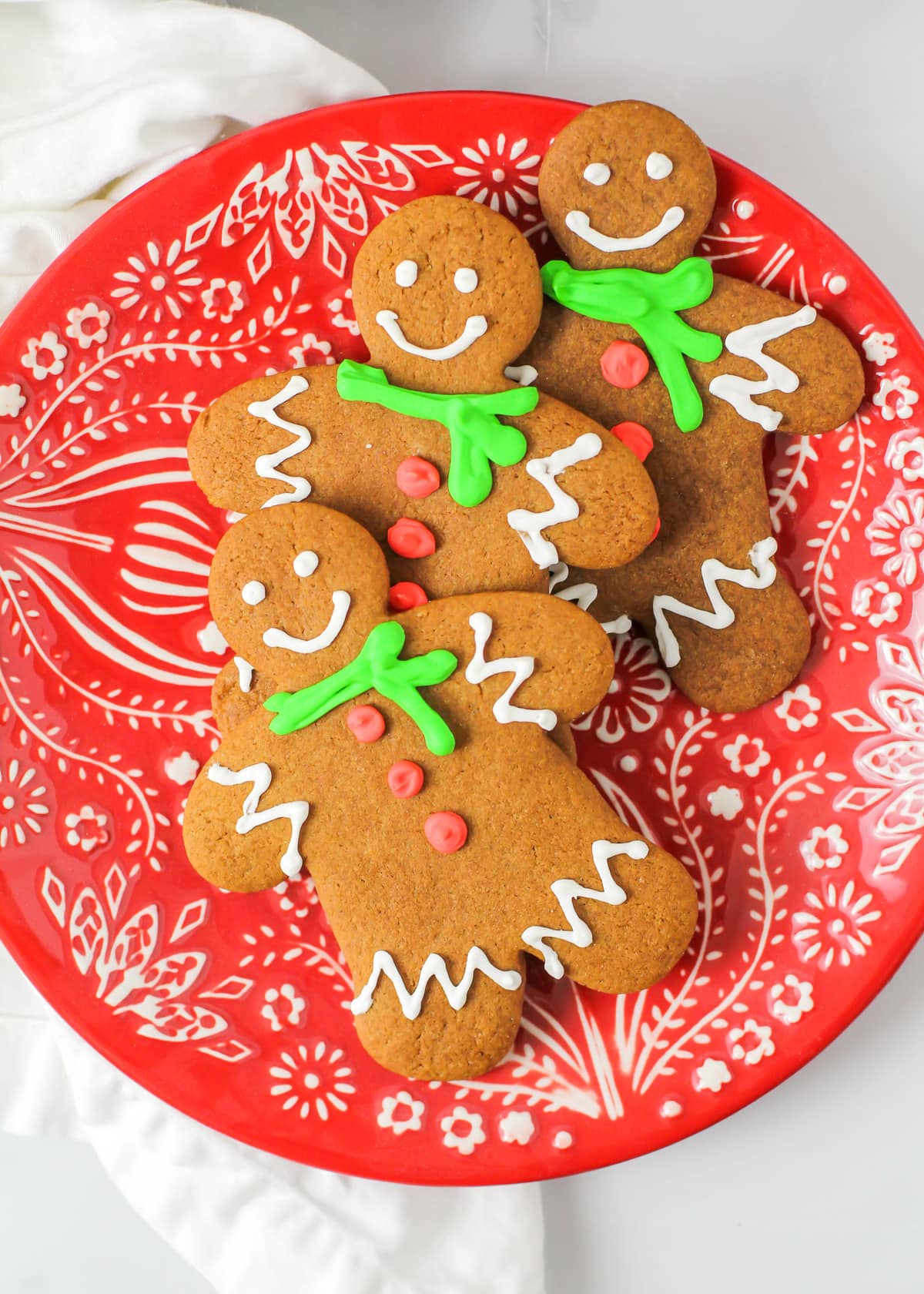 Three decorated gingerbread cookie recipe on a red plate.