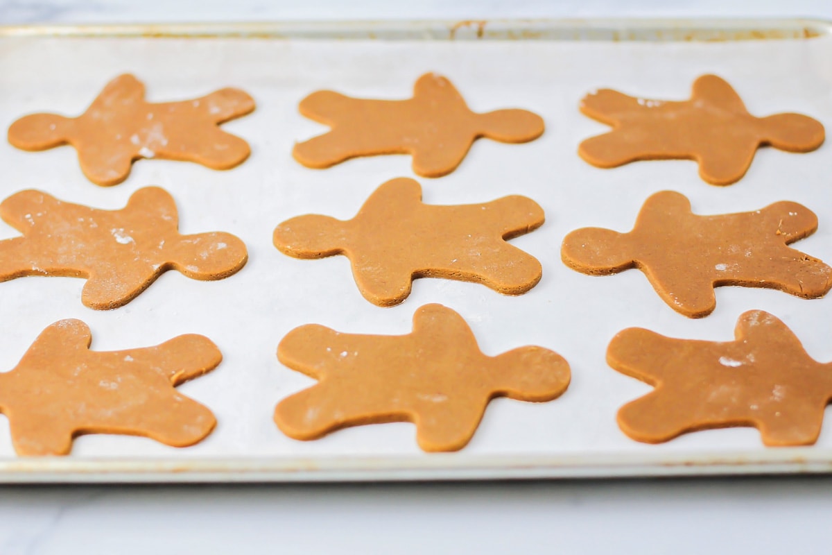 Gingerbread men cut out and placed on a lined baking sheet.