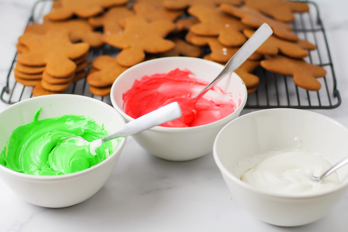 Three bowls of icing colored red, green, and white.