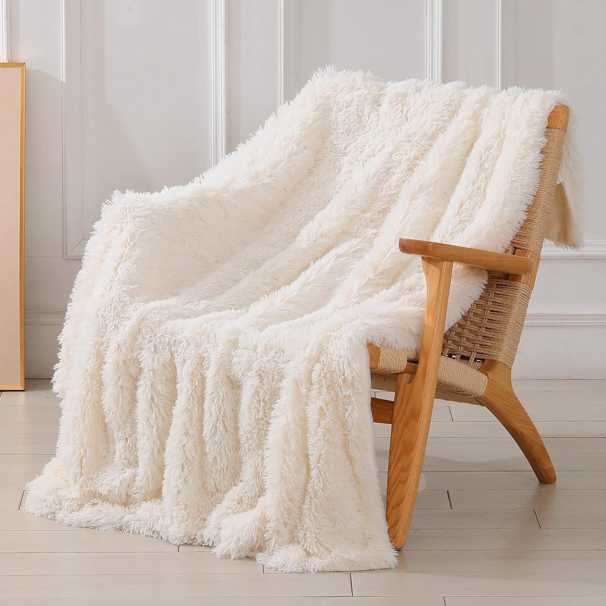 An off-white fuzzy blanket hanging over a wood chair.
