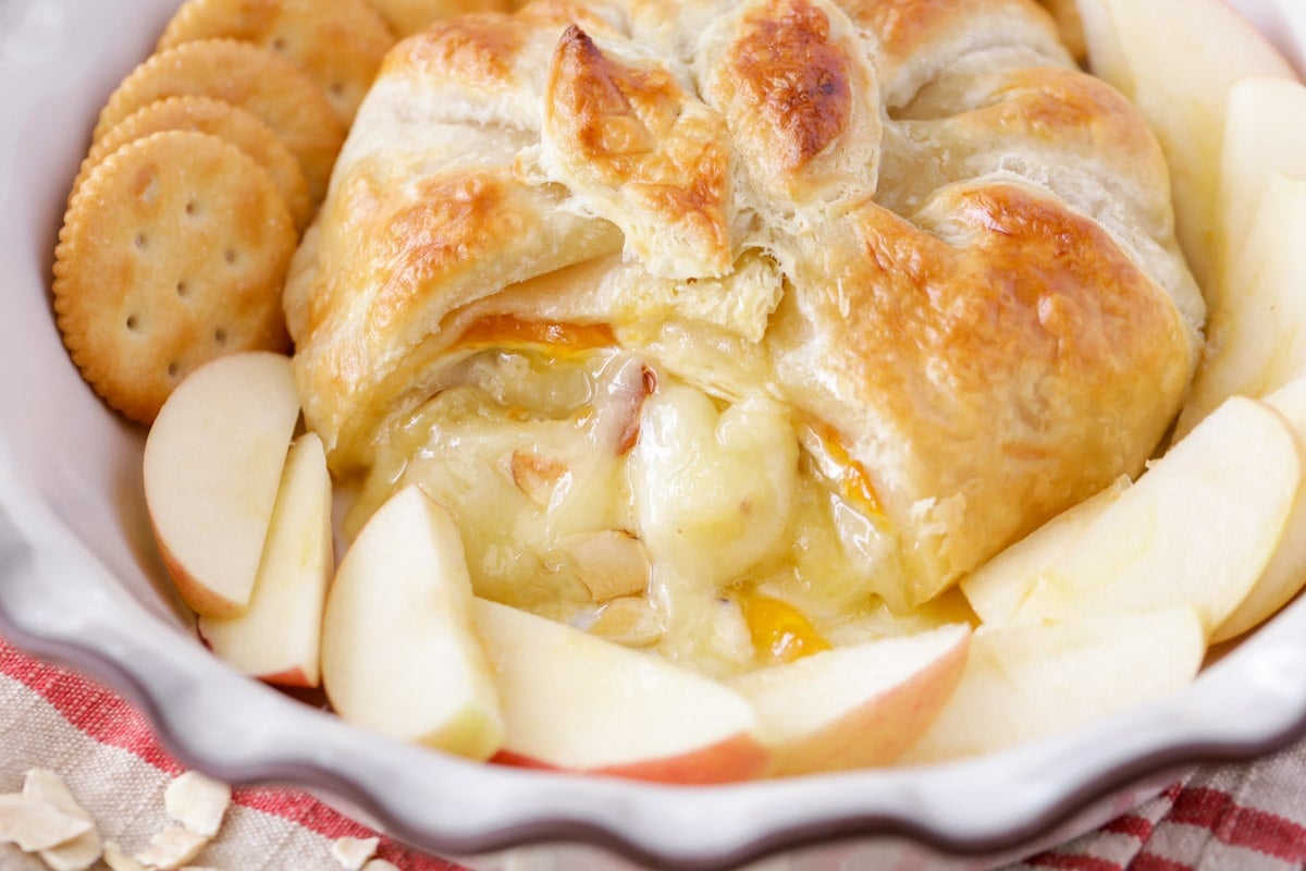 Baked brie oozing from puff pastry, served with apple slices and crackers.