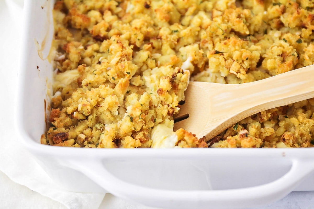 Chicken stuffing casserole with wooden spoon serving some out.