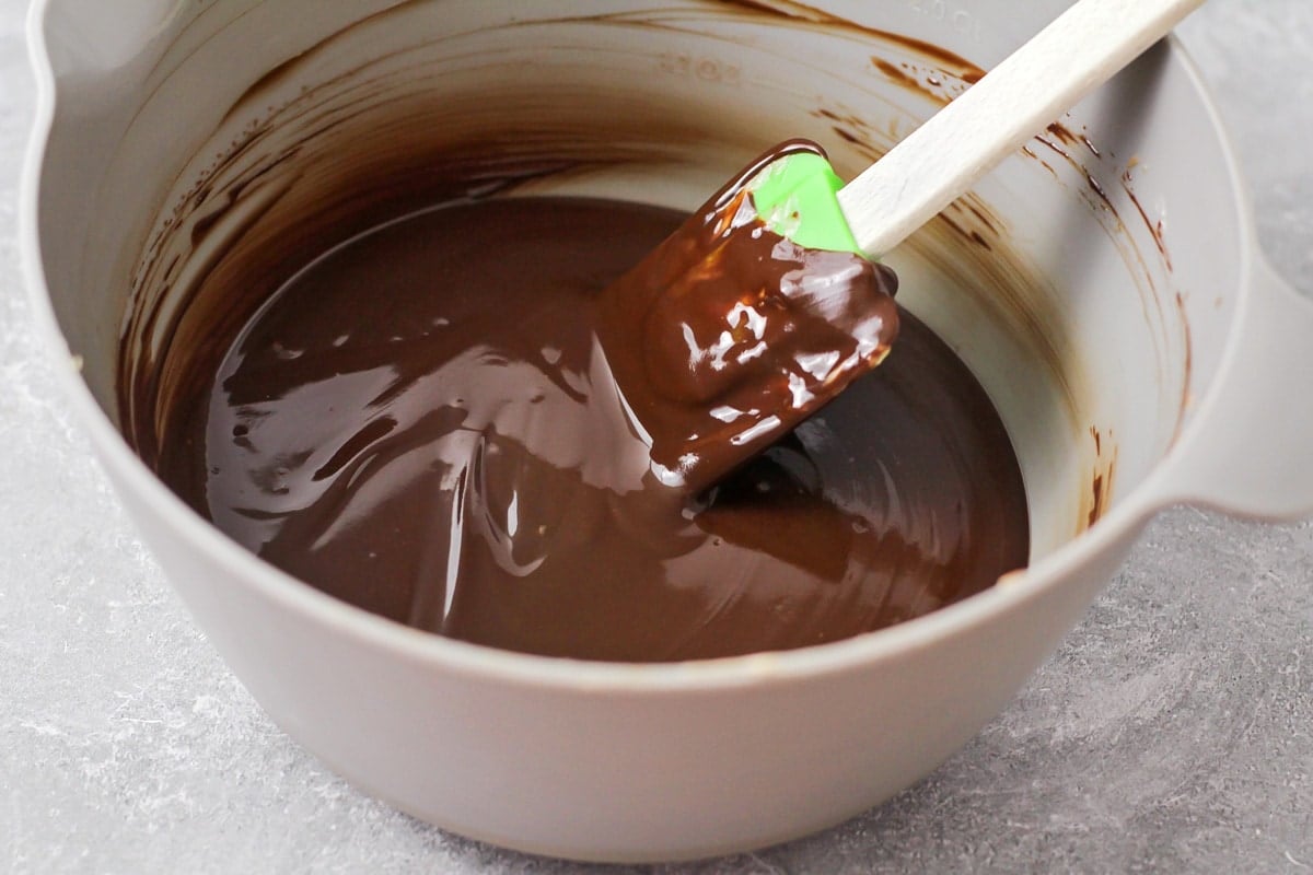 Stirring melted chocolate in a grey bowl.