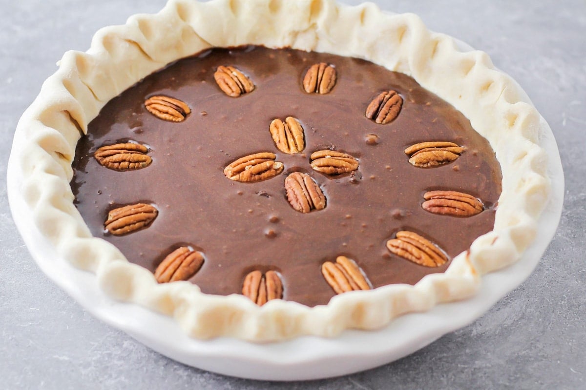 Pressing pecans into chocolate pie filling.