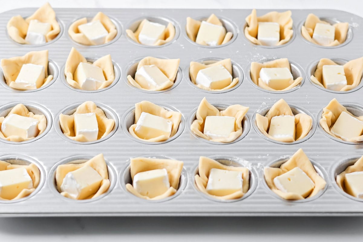 Adding brie chunks to cranberry brie bites.