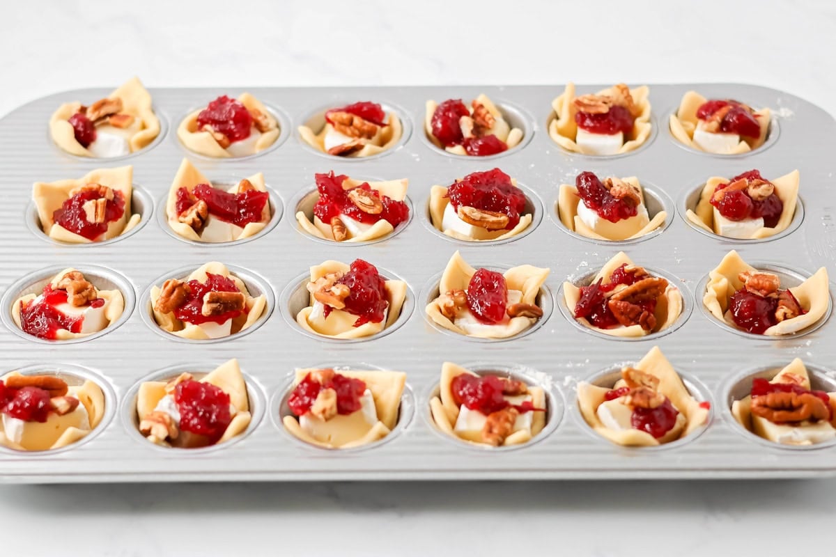 Topping cranberry brie bites with cranberry sauce.