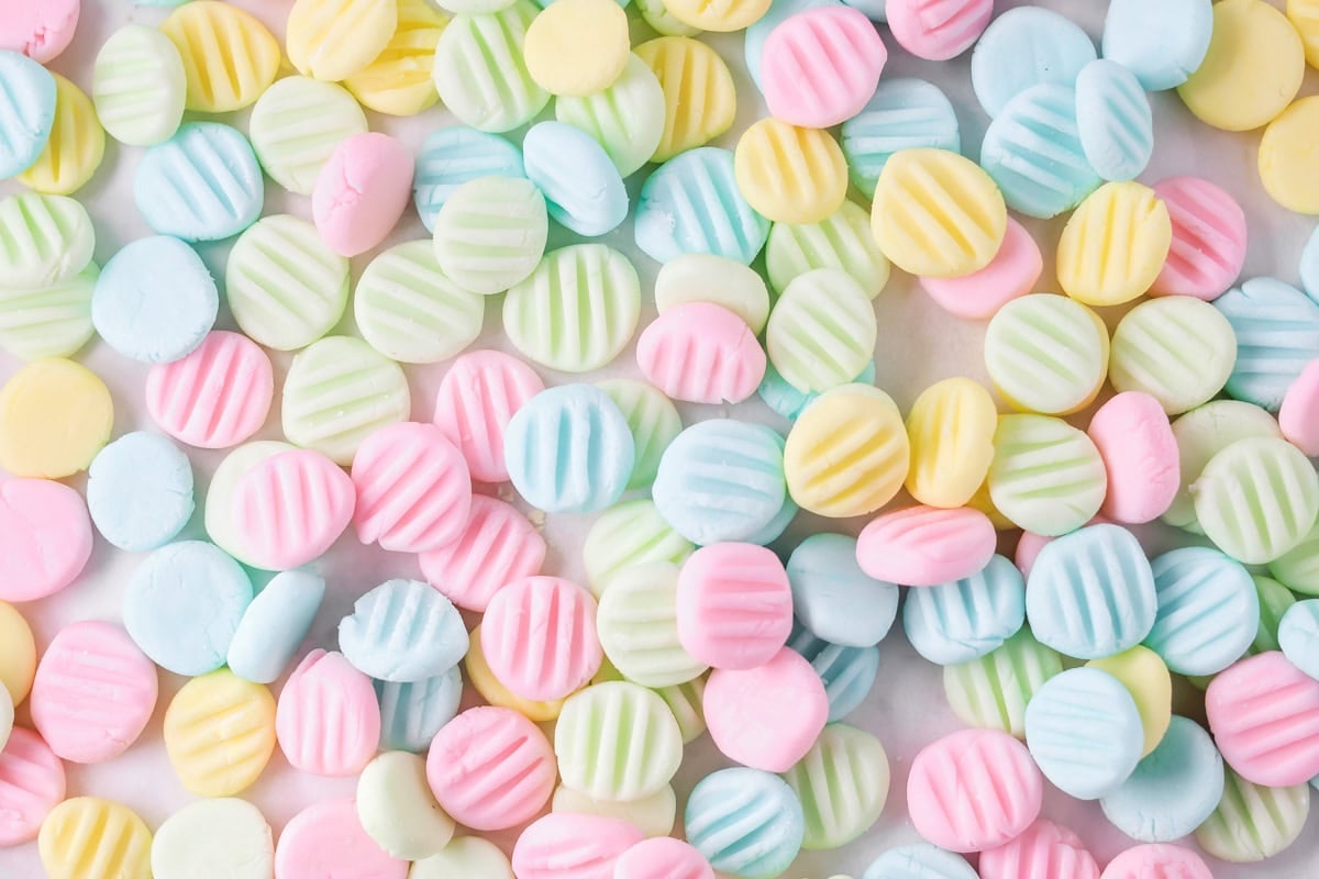 Homemade cream cheese mints on white counter top.
