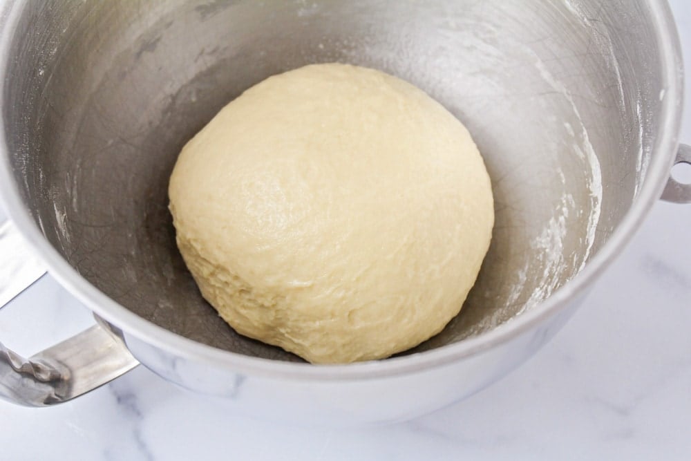 Dough shaped and rising in a metal bowl.