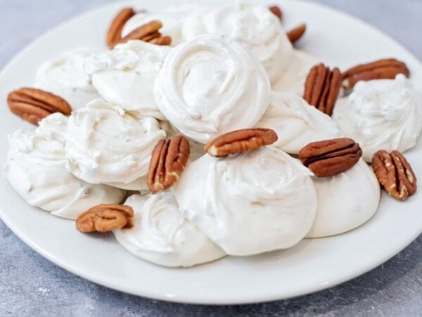Divinity recipe on a white plate with pecans.