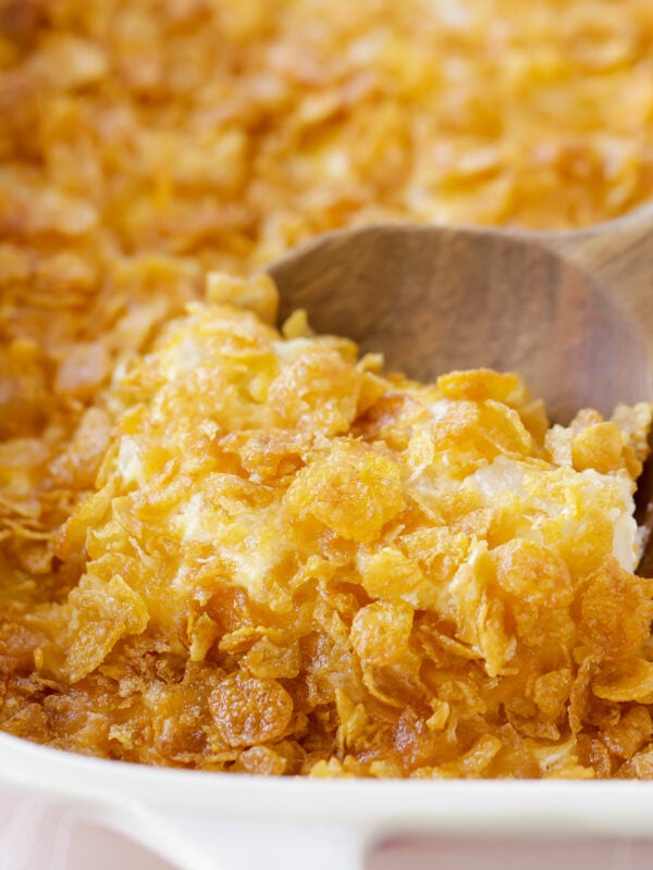 Funeral potatoes being scooped out of casserole dish.