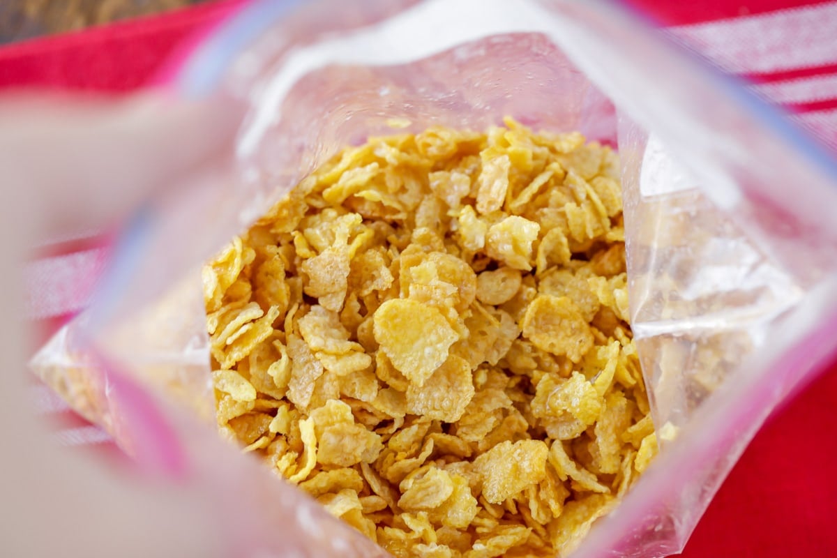 Mixing cornflakes and melted butter in a ziploc bag.