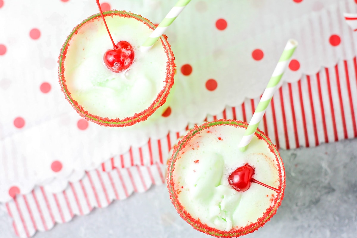 Top view of two glasses filled with green punch and topped with cherries.