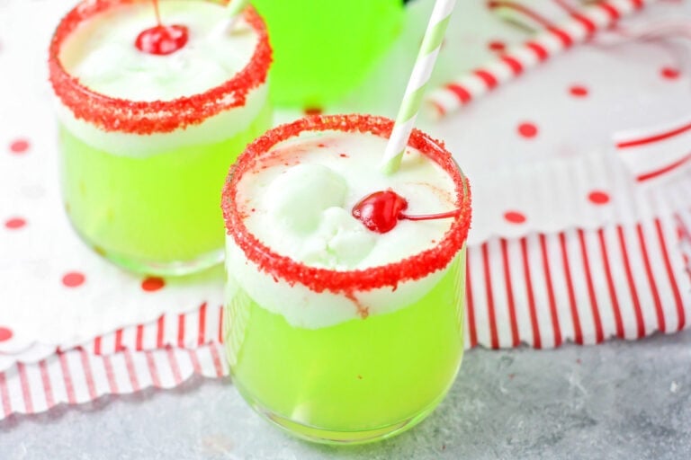 Two red sugar rimmed glasses of grinch punch recipe.