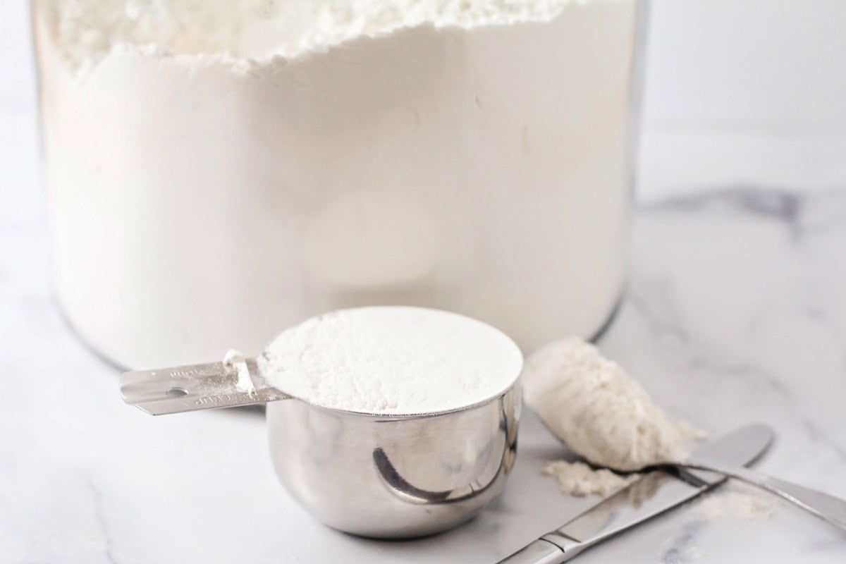 A glass jar of flour on a kitchen counter.