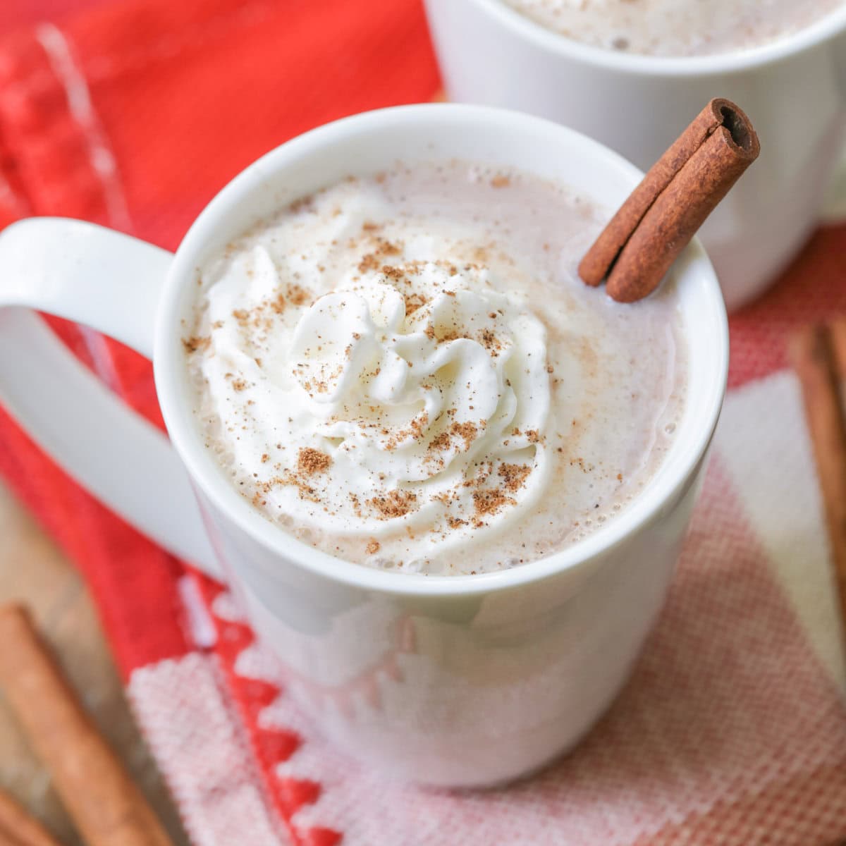 Top view of a cup of Mexican hot chocolate topped with whipped cream, nutmeg, and a cinnamon stick.