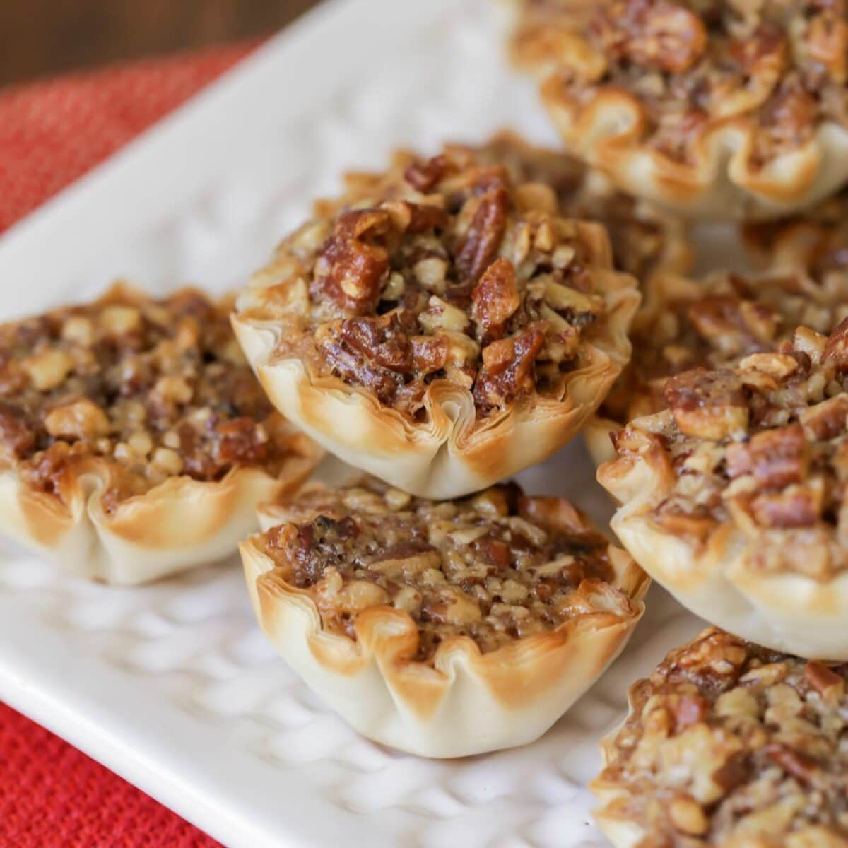 Mini Pecan Pies stacked on a white serving plate.