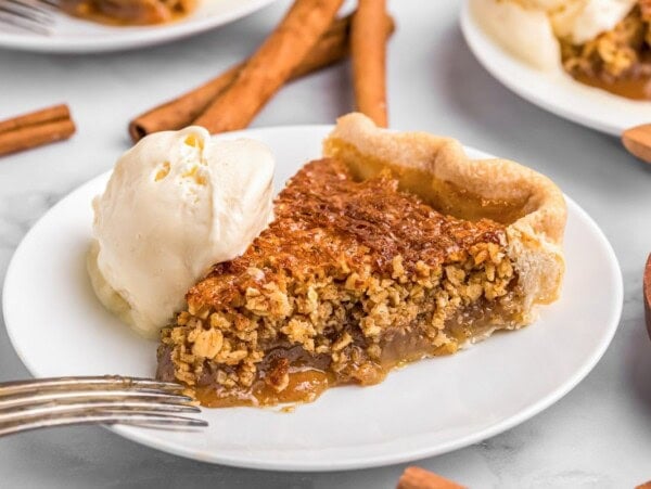 A slice of oatmeal pie on a plate served with vanilla ice cream.