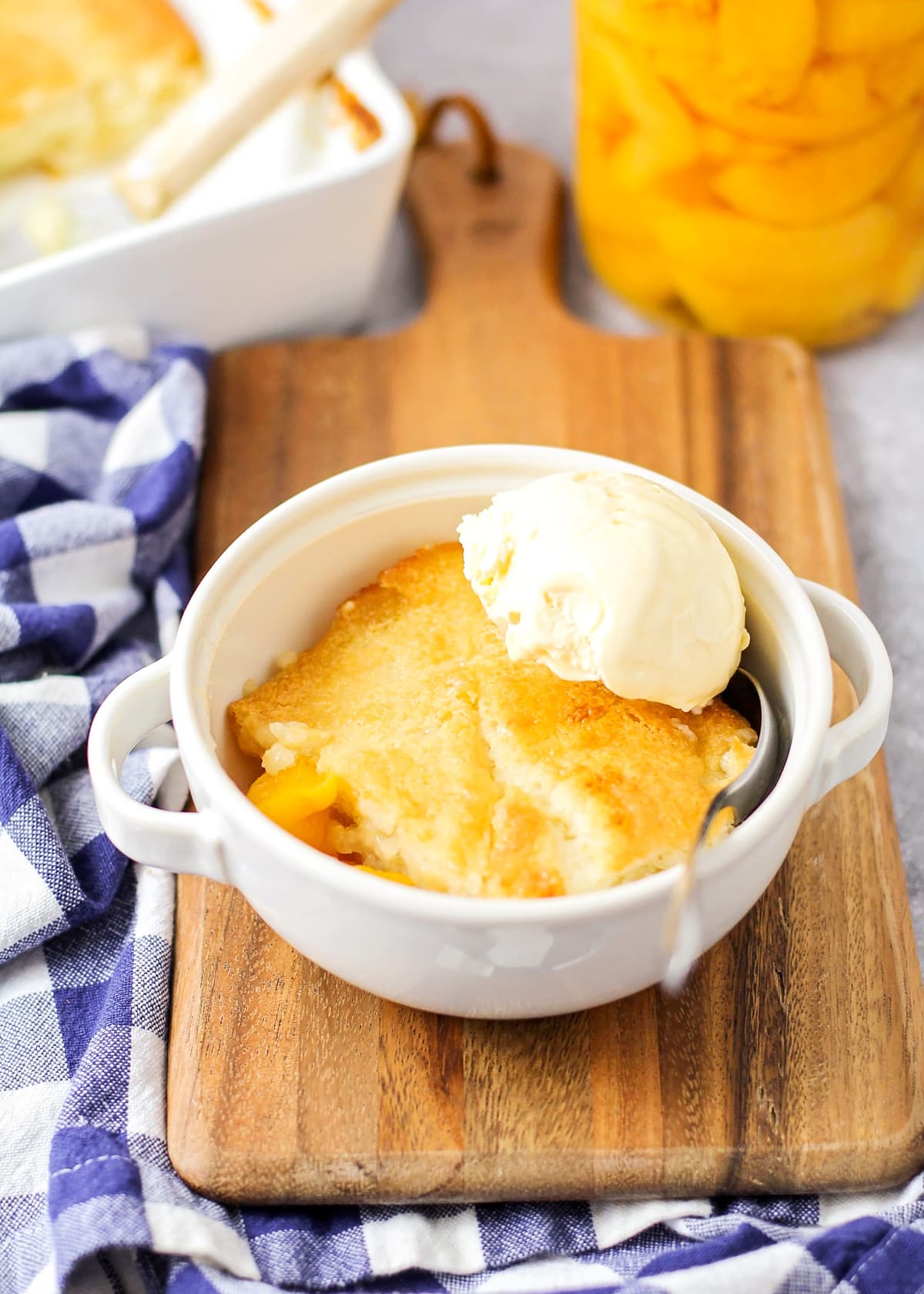Easy peach cobbler recipe in a bowl with ice cream.