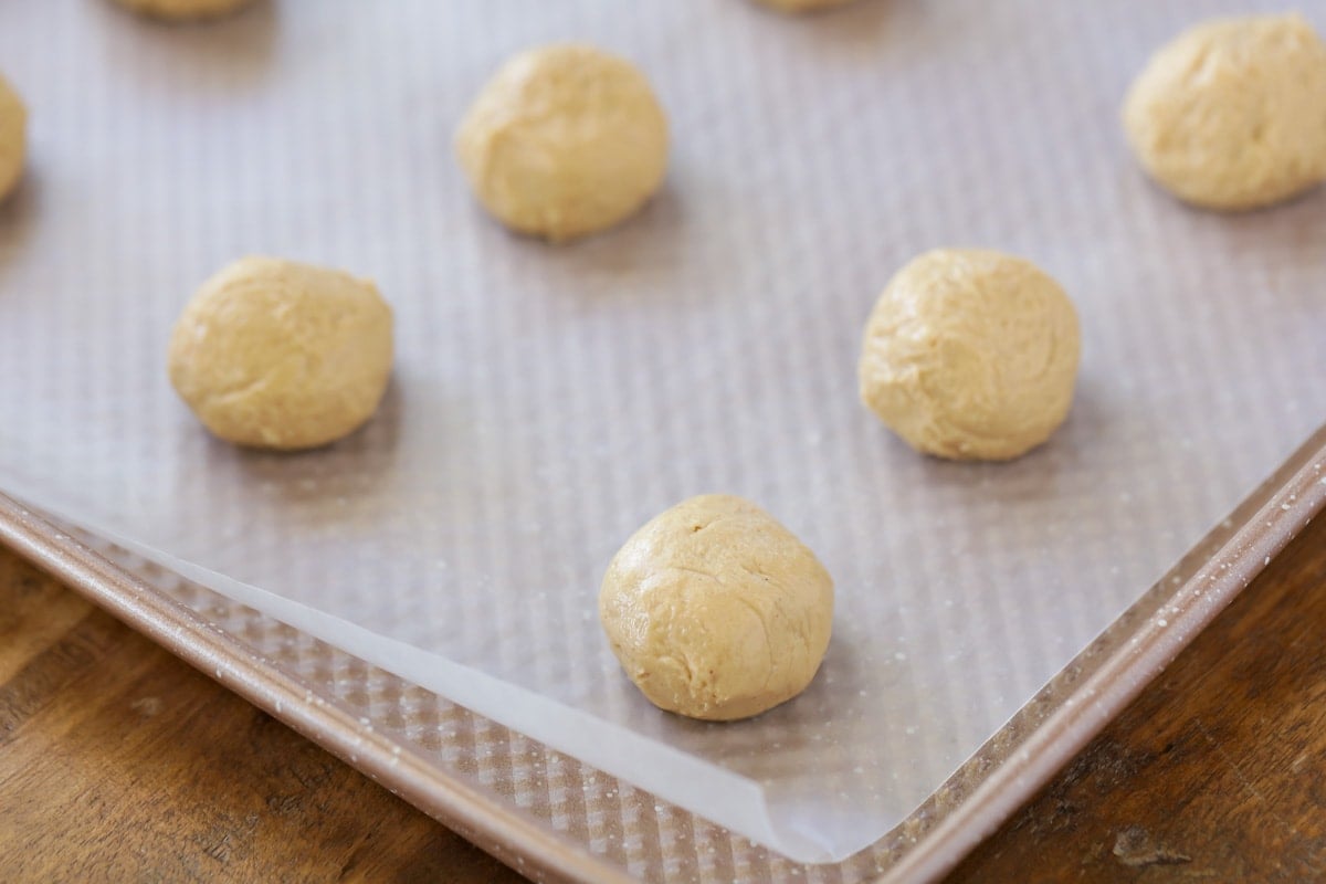 Peanut butter balls filling on a parchment lined baking sheet.