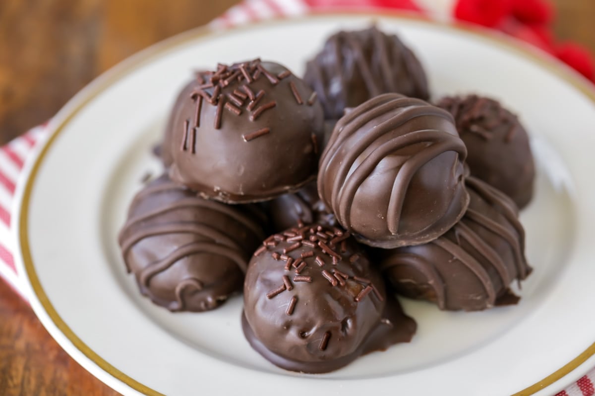 Peanut butter balls dipped in chocolate stacked on white plate.