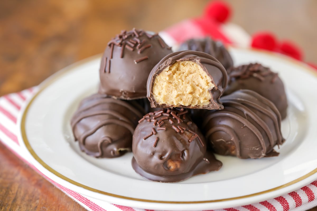 Peanut butter balls stacked on a white plate.