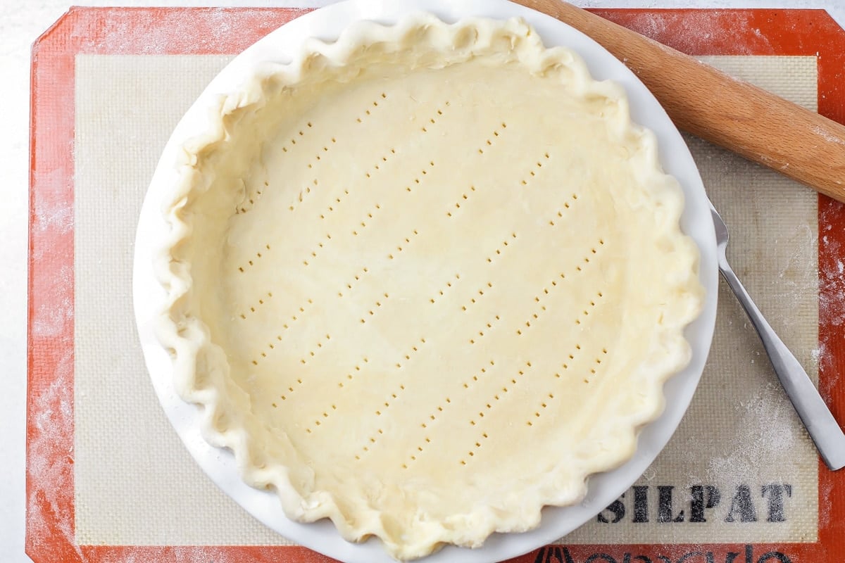 Homemade pie crust recipe in a pie pan poked with fork holes.