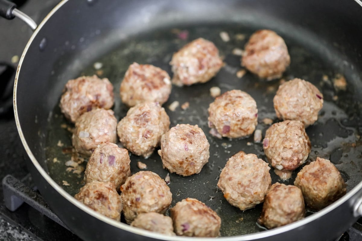 Porcupine meatballs cooking in a skillet.
