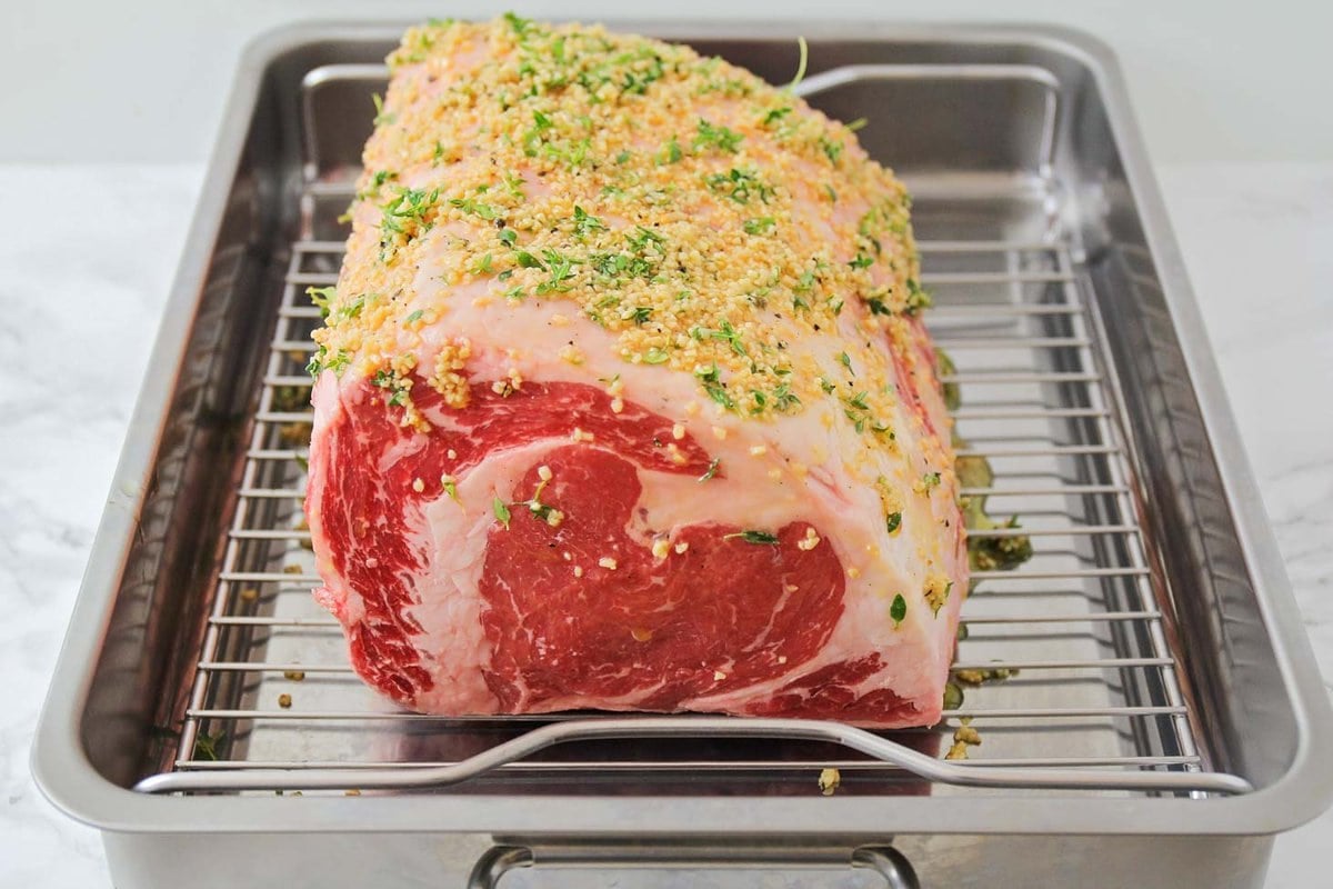 Seasoned prime rib recipe resting on a roasting pan.