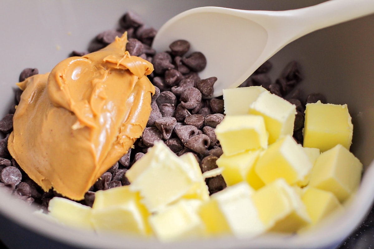 Peanut butter, chocolate chips, and butter in a grey bowl.