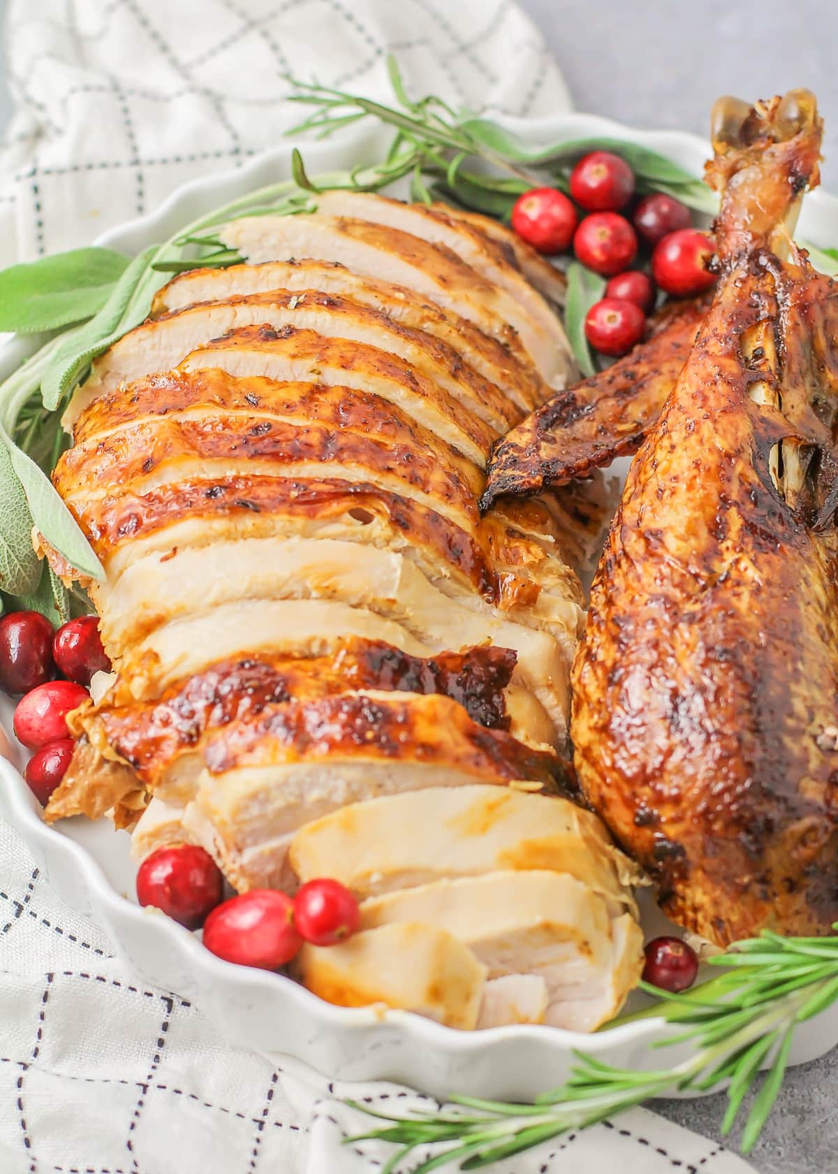 Roast turkey close up image - sliced on baking dish with fresh herbs and cranberries.