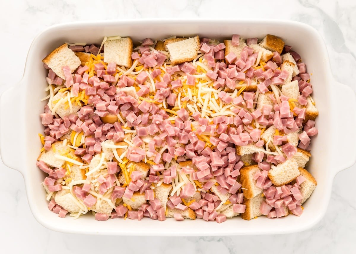Cubed bread topped with ham cubes and shredded cheese.