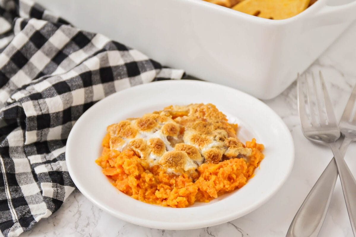 Sweet potato casserole with marshmallow scooped onto plate.