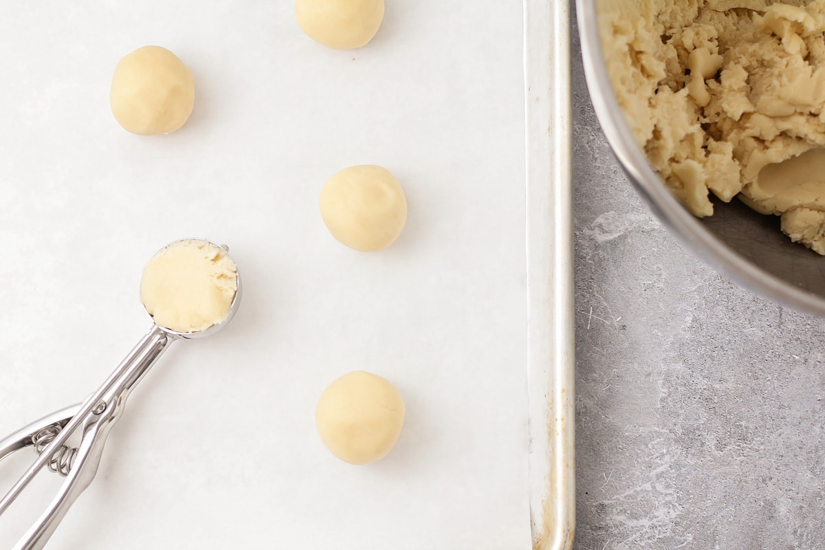 Scooping out balls of cookie dough onto a cookie sheet.