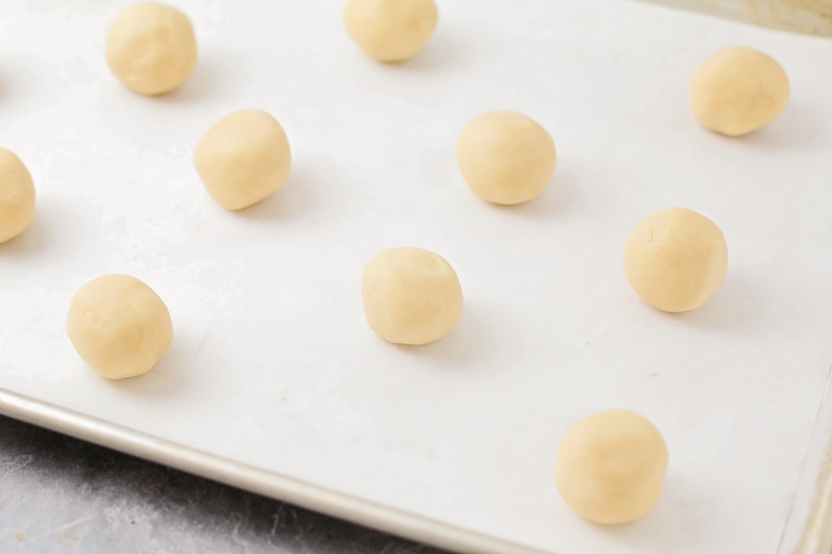 Balls of cookie dough placed on a lined cookie sheet.