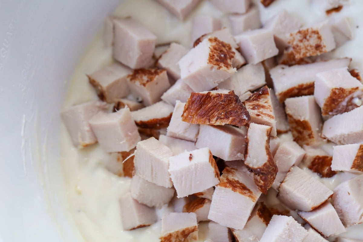 Turkey chunks mixed in bowl with cream mixture.